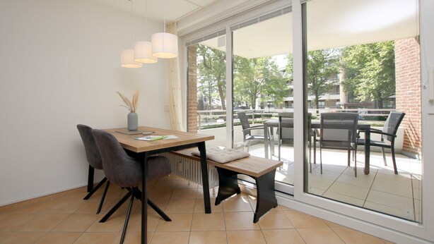 A modern dining area with a table, chairs, and pendant lighting.