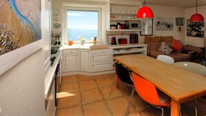 Una cucina con mobili bianchi, un tavolo in legno e lampade a sospensione rosse.