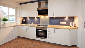 A kitchen with white cabinets, a stainless steel oven, and a window with a view of the outside.