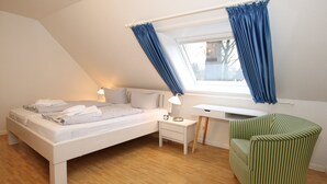 Een slaapkamer met een bed, nachtkastje, lamp en een stoel.