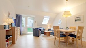 Een gezellige woonkamer met een eettafel, stoelen, een bank en een lamp.