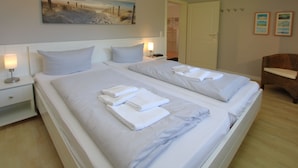 Une chambre d’hôtel avec deux lits, une table de chevet, une lampe et un tableau au mur.