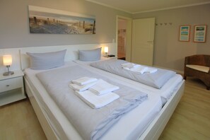 Et hotelværelse med to senge, et natbord, en lampe og et billede på væggen.
