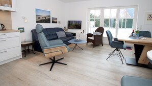 A modern living room with a sofa, chairs, a dining table, and artwork on the walls. - Vacation apartment with 3 rooms on approx. 53m² (Wyk auf Föhr)