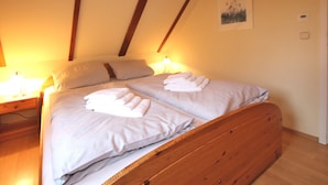 Ein Schlafzimmer mit einem hölzernen Bett, zwei Kissen und einem Nachttisch mit einer Lampe.