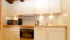 Eine Küche mit weißen Schränken, einer Mikrowelle, einer Kaffeemaschine und einem Backofen.