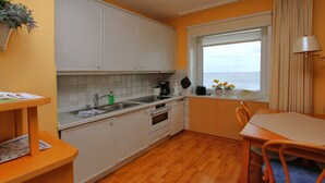 Une cuisine de taille réduite avec des meubles blancs, un plan de travail en bois et une fenêtre offrant une belle vue.