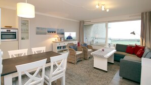 Una sala moderna con comedor, cocina y balcón con vistas.