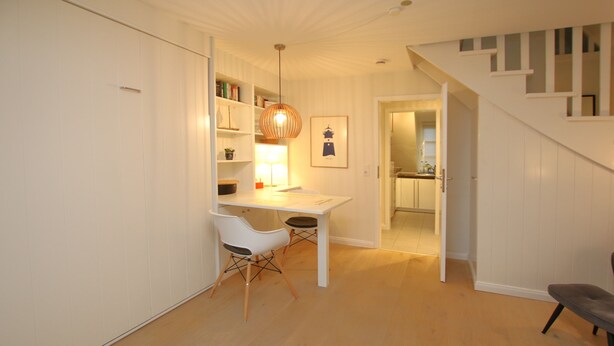 A modern kitchen with white cabinets, a wooden countertop, and a hanging light fixture. - Ferienwohnung mit 2- Zimmern auf ca. 35m² (Wyk auf Föhr)