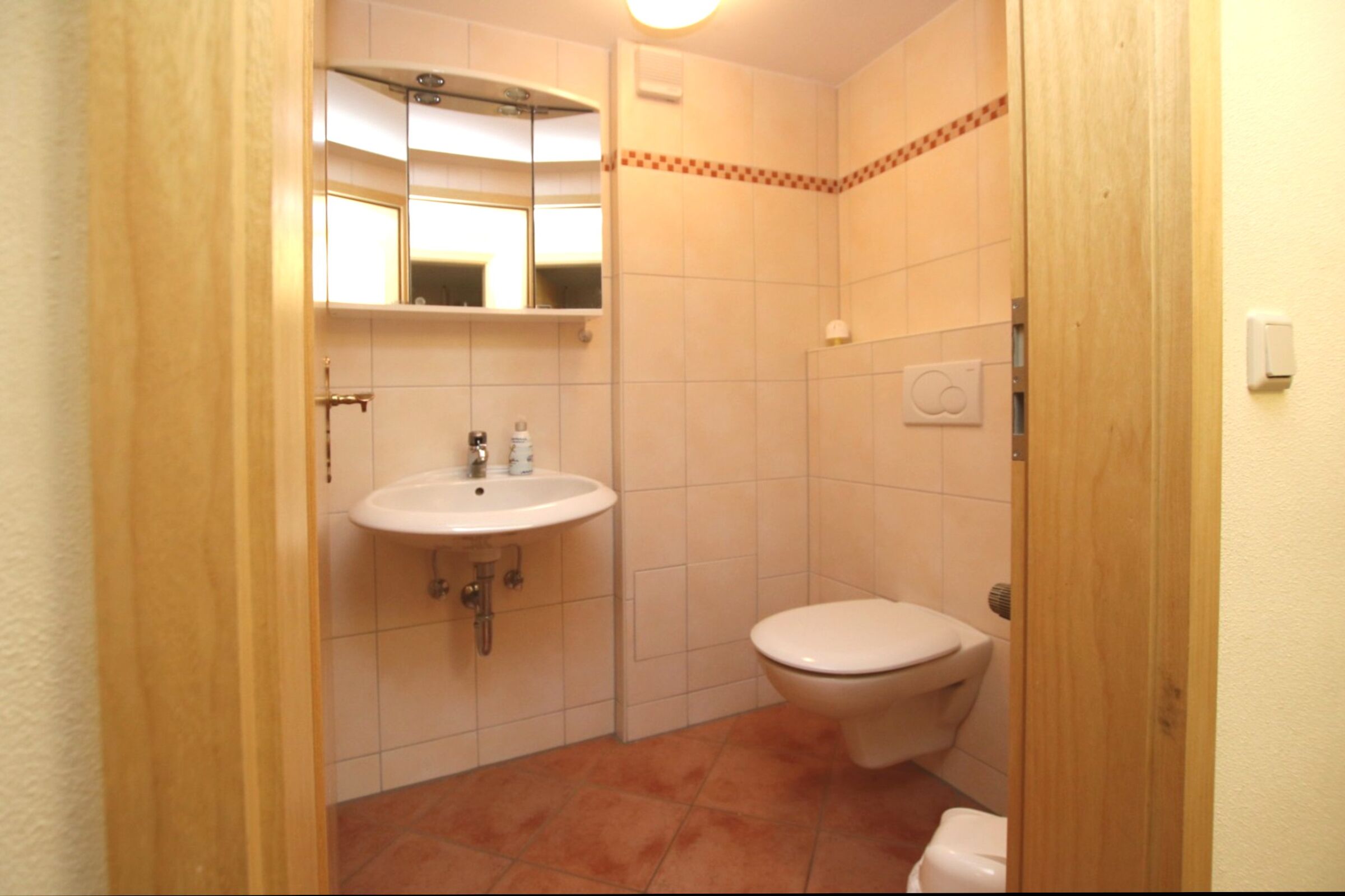 Ein kleines Badezimmer mit Waschbecken, Toilette und Spiegel.