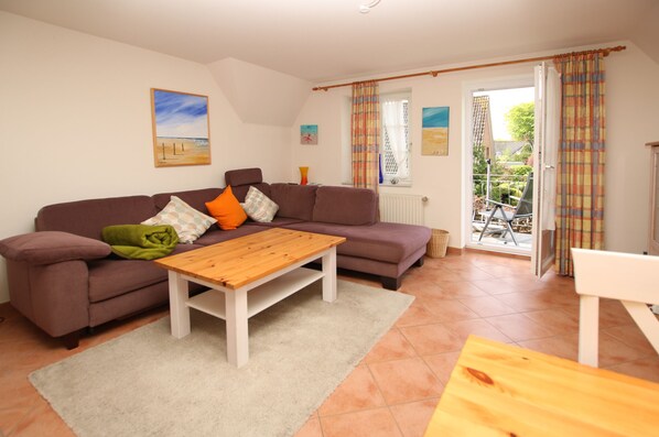 A living room with a sofa, a wooden coffee table, and a window with curtains.