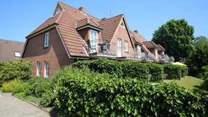 A row of red brick houses with sloped roofs and balconies. - Ferienwohnung mit 2- Zimmern auf ca. 35m² (Wyk auf Föhr)