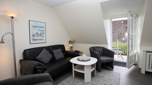 A modern living room with a black sofa, a white coffee table, and a lamp. - Ferienwohnung mit 2- Zimmern auf ca. 35m² (Wyk auf Föhr)