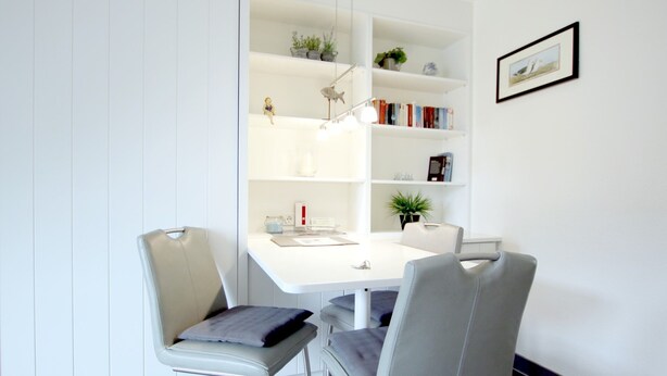 A modern room with a white desk, two chairs, a bookshelf, and a framed picture on the wall. - Ferienwohnung mit 2- Zimmern auf ca. 35m² (Wyk auf Föhr)