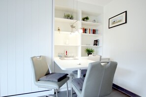 A modern room with a white desk, two chairs, a bookshelf, and a framed picture on the wall. - Ferienwohnung mit 2- Zimmern auf ca. 35m² (Wyk auf Föhr)