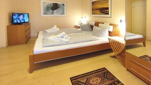 A hotel room with a large bed, two bedside tables, a TV, and artwork on the walls.