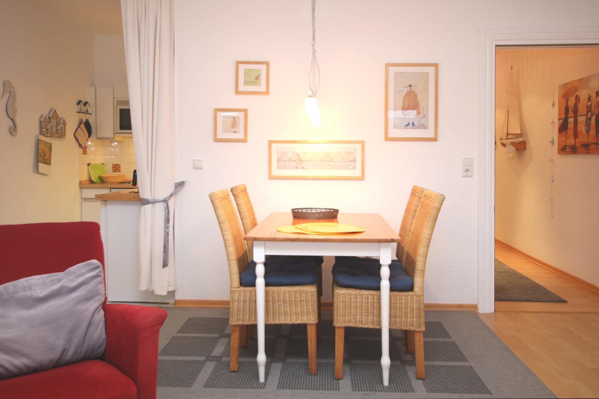 Un comedor con una mesa y sillas, un sofá rojo y una cocina al fondo.