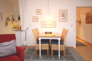 Un coin repas avec une table et des chaises, un canapé rouge et, au fond, une cuisine.