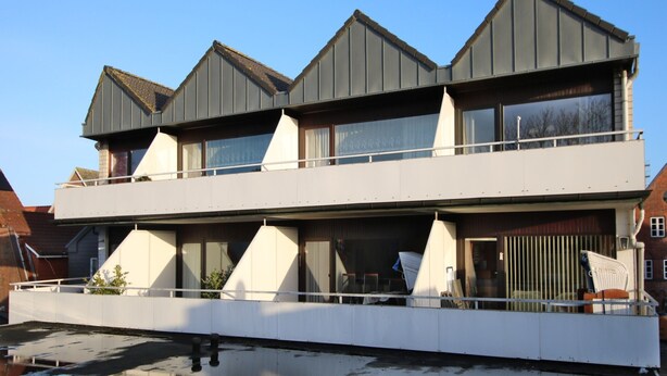 A modern two-story building with a flat roof and large windows.