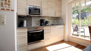 A kitchen with light wood cabinets, stainless steel appliances, a window with a view of the outdoors, and a tiled backsplash.