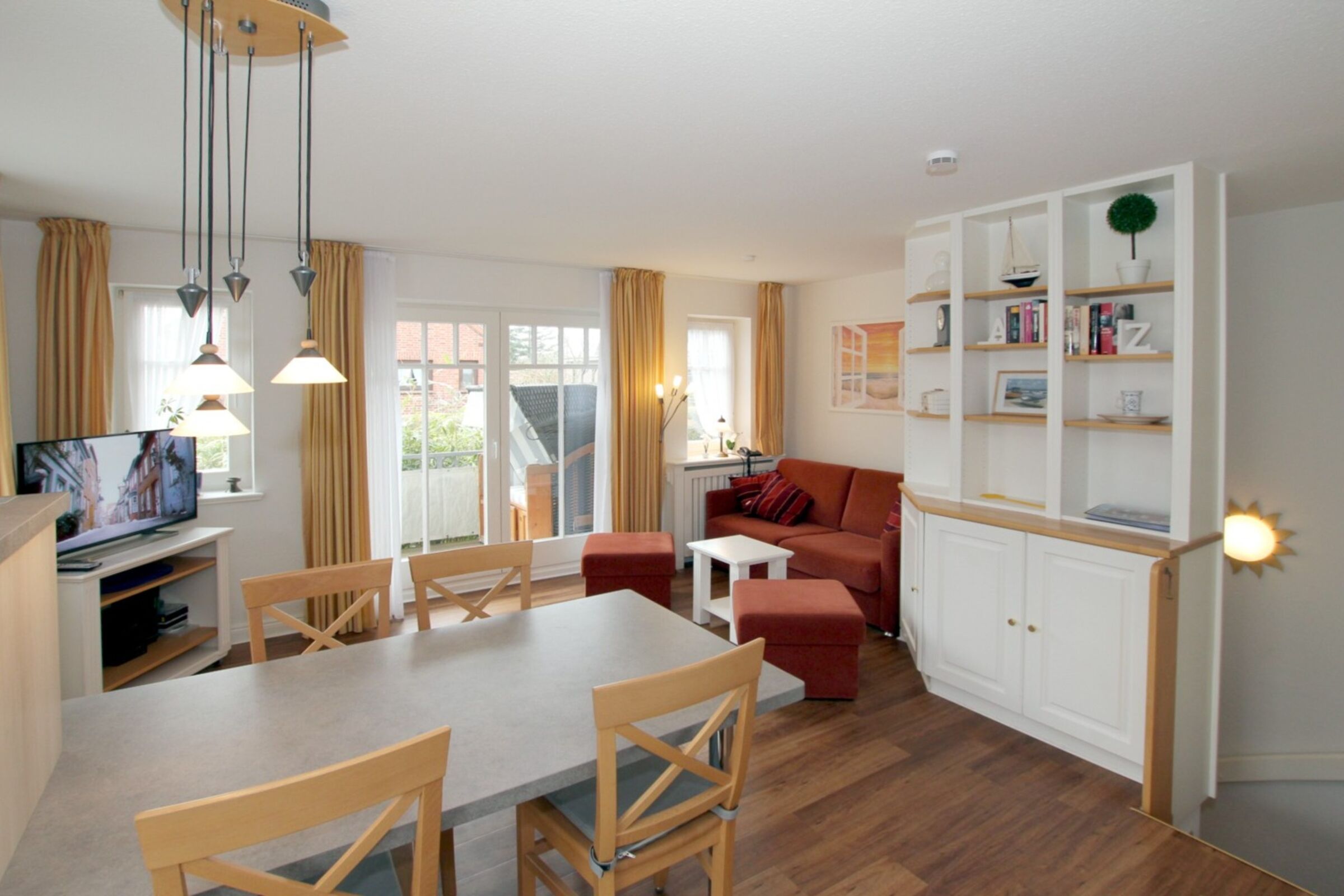 Una sala de estar moderna con comedor, un sofá rojo y una estantería blanca.
