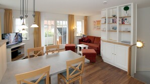 A modern living room with a dining area, a red sofa, and a white bookshelf.