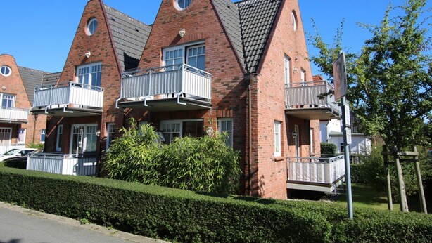 A row of brick houses with unique triangular roofs and balconies. - Ferienwohnung mit 3- Zimmern auf ca. 55m² für Max. 2 Erwachsene und 2 Kinder (Wyk auf Föhr)