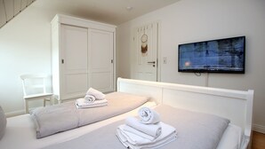 Una habitación de hotel con dos camas, televisión y un armario.