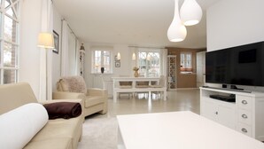 Una sala de estar moderna con un sofá, una mesa de centro y un televisor sobre un mueble.