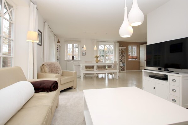 A modern living room with a sofa, a coffee table, and a TV on a stand.