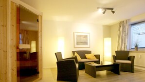 Una sala de estar con un sofá, dos sillones, una mesa de centro y un cuadro en la pared.