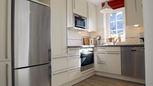 Una cocina moderna con electrodomésticos de acero inoxidable, armarios blancos y un ventanal que proporciona luz natural.