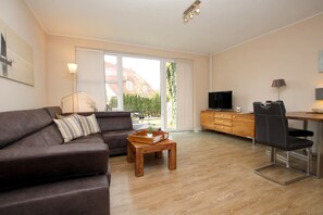 A modern living room with a sofa, coffee table, and a TV. - Ferienwohnung am Südstrand von Wyk, mit 2 Zimmern auf ca. 44 m² im Erdgeschoß (Wyk auf Föhr)
