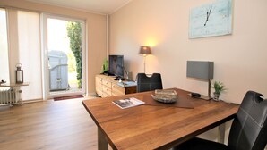 A dining area with a wooden table, black chairs, a lamp, and a clock on the wall. - Ferienwohnung am Südstrand von Wyk, mit 2 Zimmern auf ca. 44 m² im Erdgeschoß (Wyk auf Föhr)