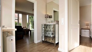 A hallway with a wooden floor, a white door, a mirror, and a dresser with alphabet letters. - Ferienwohnung am Südstrand von Wyk, mit 2 Zimmern auf ca. 44 m² im Erdgeschoß (Wyk auf Föhr)