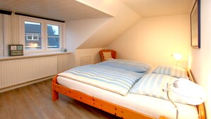 Une chambre avec un lit en bois, une fenêtre donnant sur un beau paysage, une lampe de chevet et un radiateur.