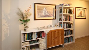 Une bibliothèque avec des étagères, un meuble en bois et des œuvres d’art encadrées accrochées au mur.