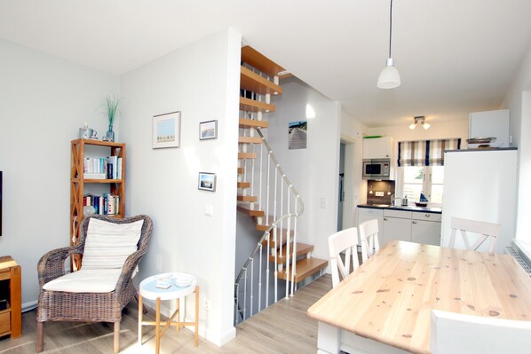 A modern kitchen with a dining area, a staircase, and a bookshelf.