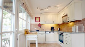 A modern kitchen with white cabinets, a built-in oven, and a coffee maker. - Ferienwohnung mit 3- Zimmern Über ca. 100m² im Obergeschoß und Spitzboden (Wyk auf Föhr)