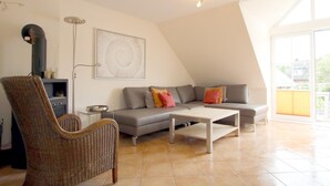 A modern living room with a grey sofa, a white coffee table, and a wicker chair. - Ferienwohnung mit 3- Zimmern Über ca. 100m² im Obergeschoß und Spitzboden (Wyk auf Föhr)