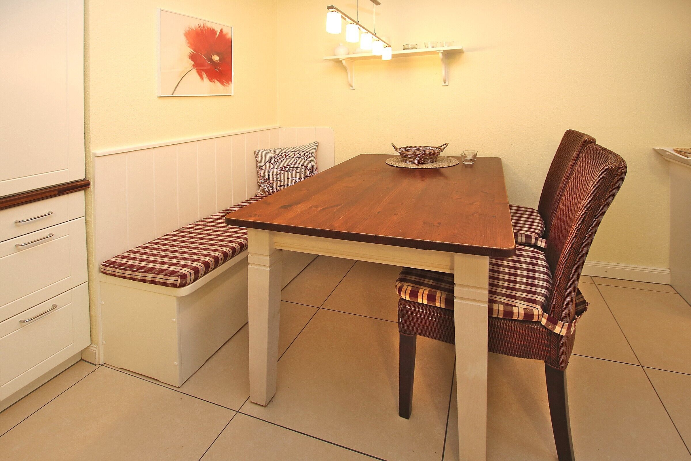 Un comedor con mesa de madera, bancos y sillas de mimbre.