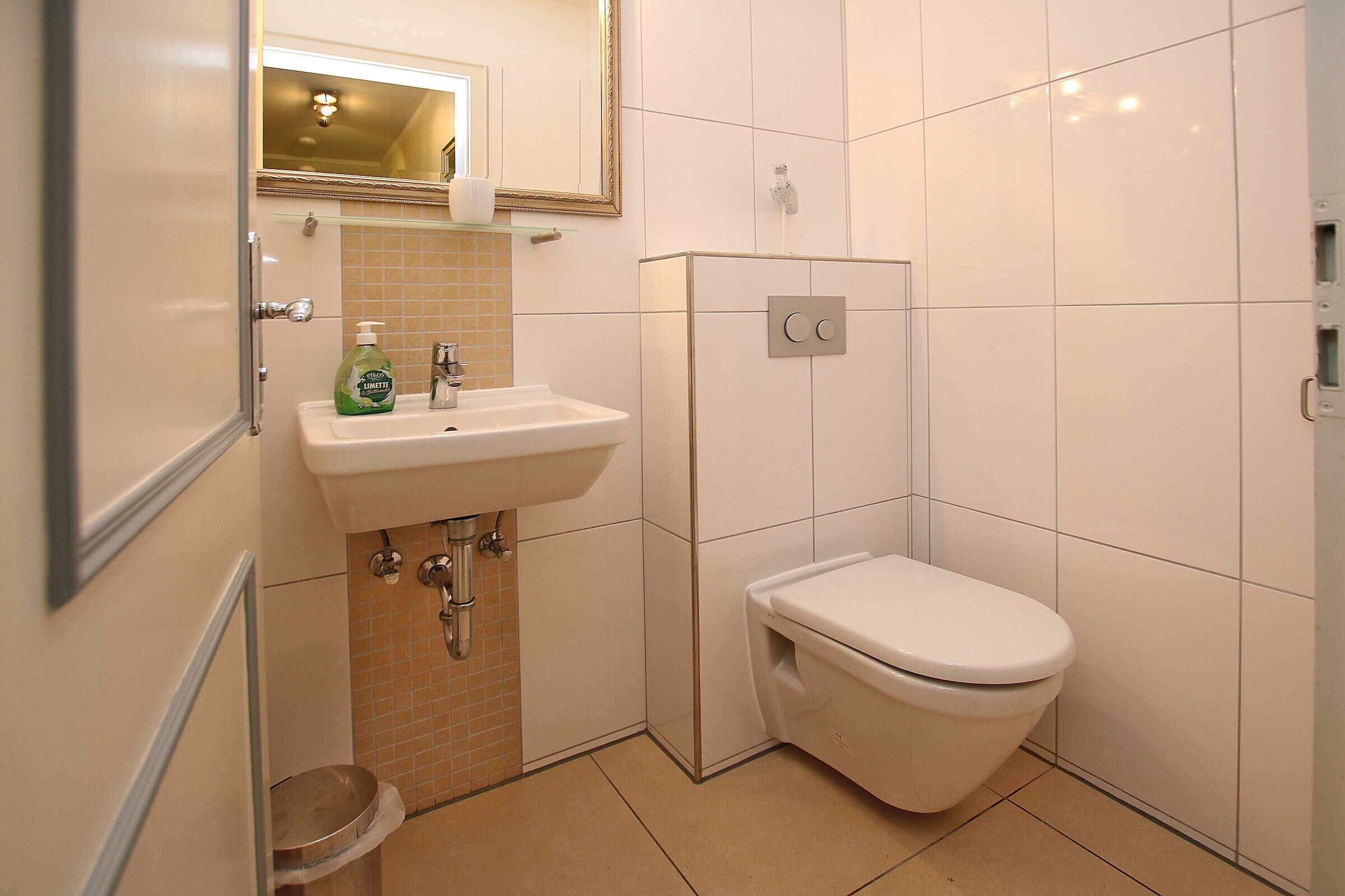 A bathroom with a white sink, a toilet, and a mirror.