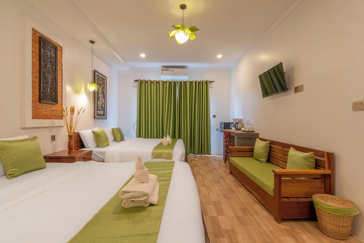 Une chambre d’hôtel avec deux lits, un canapé, une télévision et un bureau avec une chaise.