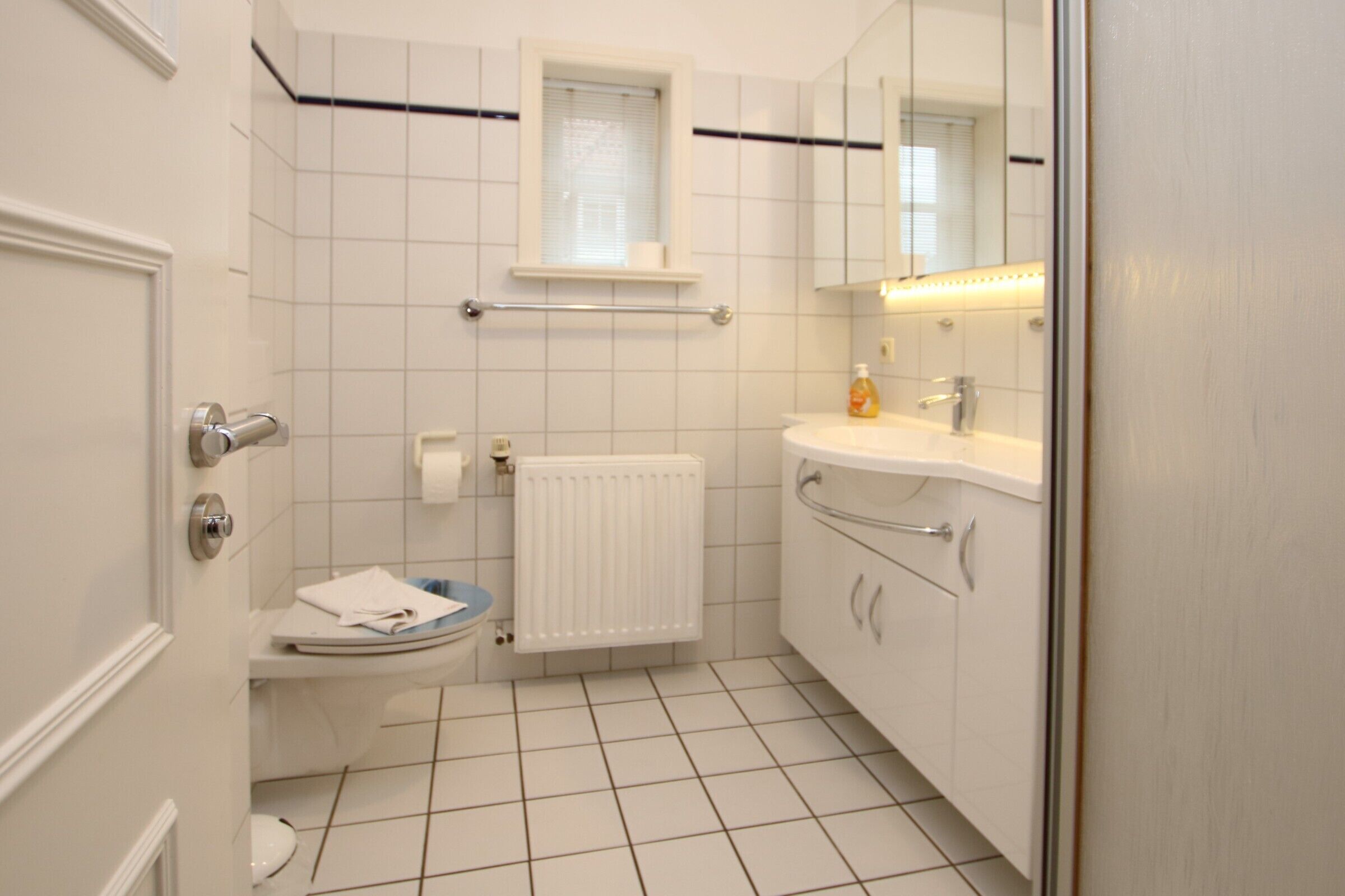 A small, clean bathroom with a toilet, sink, and mirror.