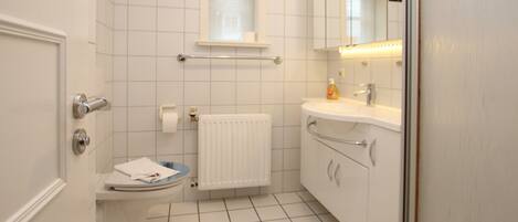 A small, clean bathroom with a toilet, sink, and mirror.