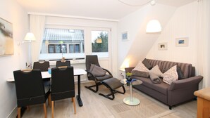 En moderne stue med en brun sofa, sorte stole, et spisebord og et lille sofabord med en lampe.