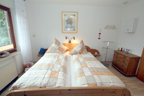 Une chambre à coucher avec un lit, une commode, une lampe et une fenêtre.