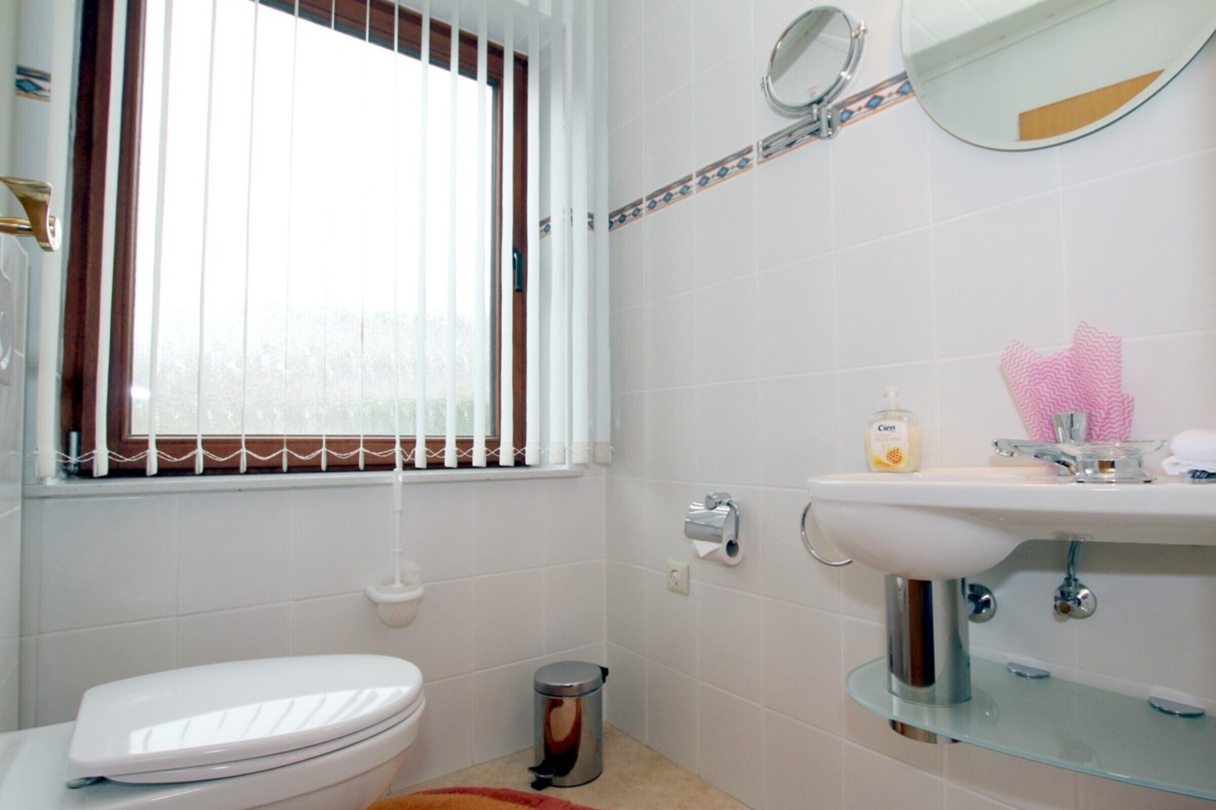 A bathroom with a toilet, sink, and window with blinds.