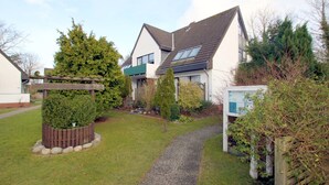 A residential property with a well-maintained lawn, a gravel pathway, and a wooden fence.