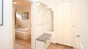 A bedroom with a bed, a bedside table, a mirror, and a wardrobe.